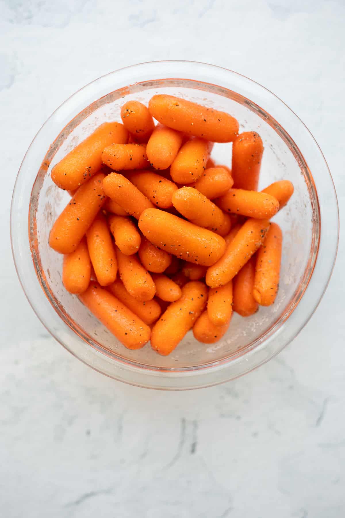 baby carrots seasoned in a glass bowl.