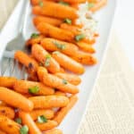air fryer baby carrots topped with fresh herbs on a white platter.