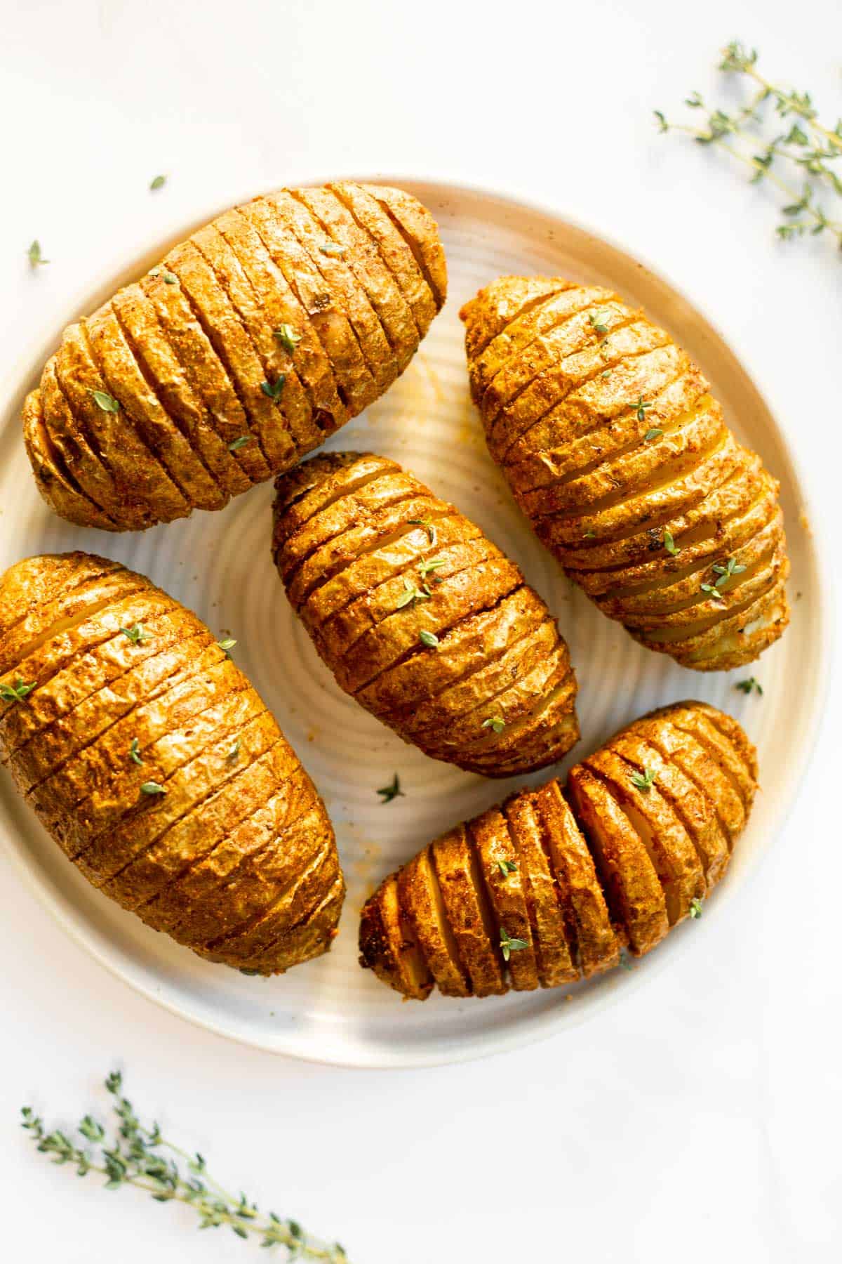 5 hasselback potatoes on a white plate.