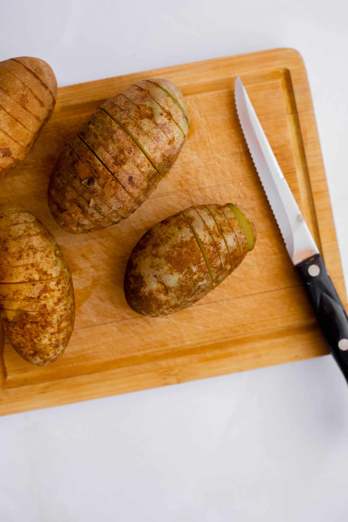 potatoes sliced into fan shaped on a cutting board.