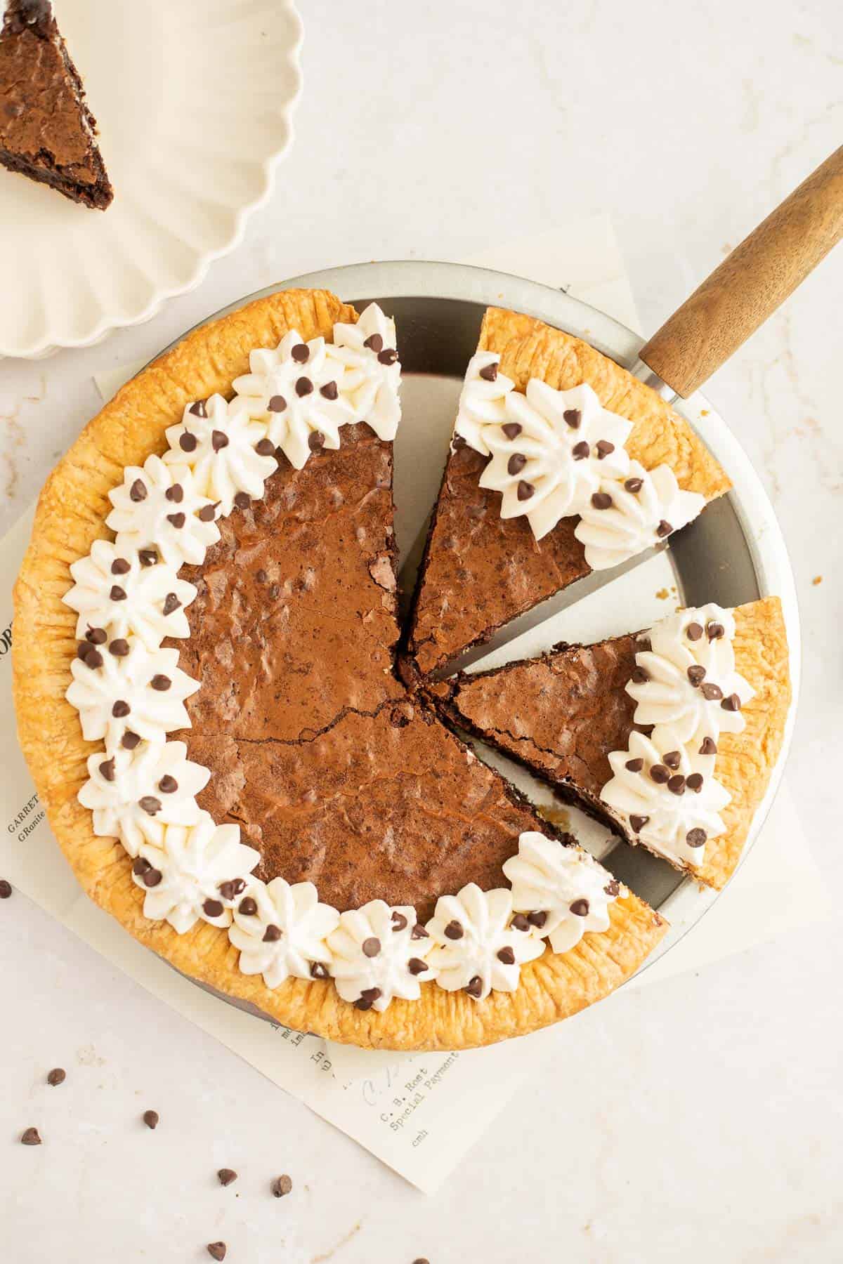 brownie pie cut into slices topped with whipped cream and chocolate chips.