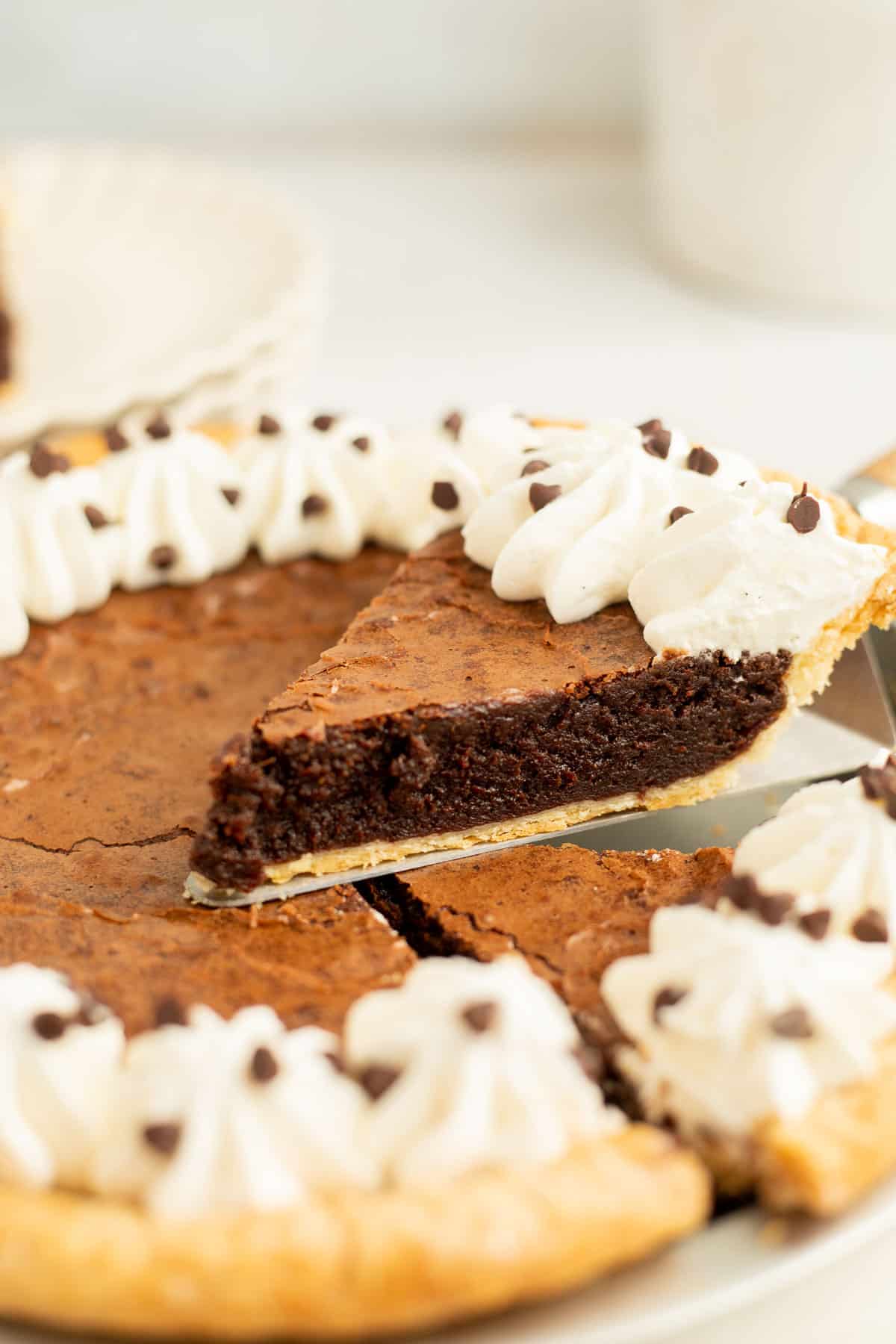 a slice of brownie pie resting on top of the whole pie.