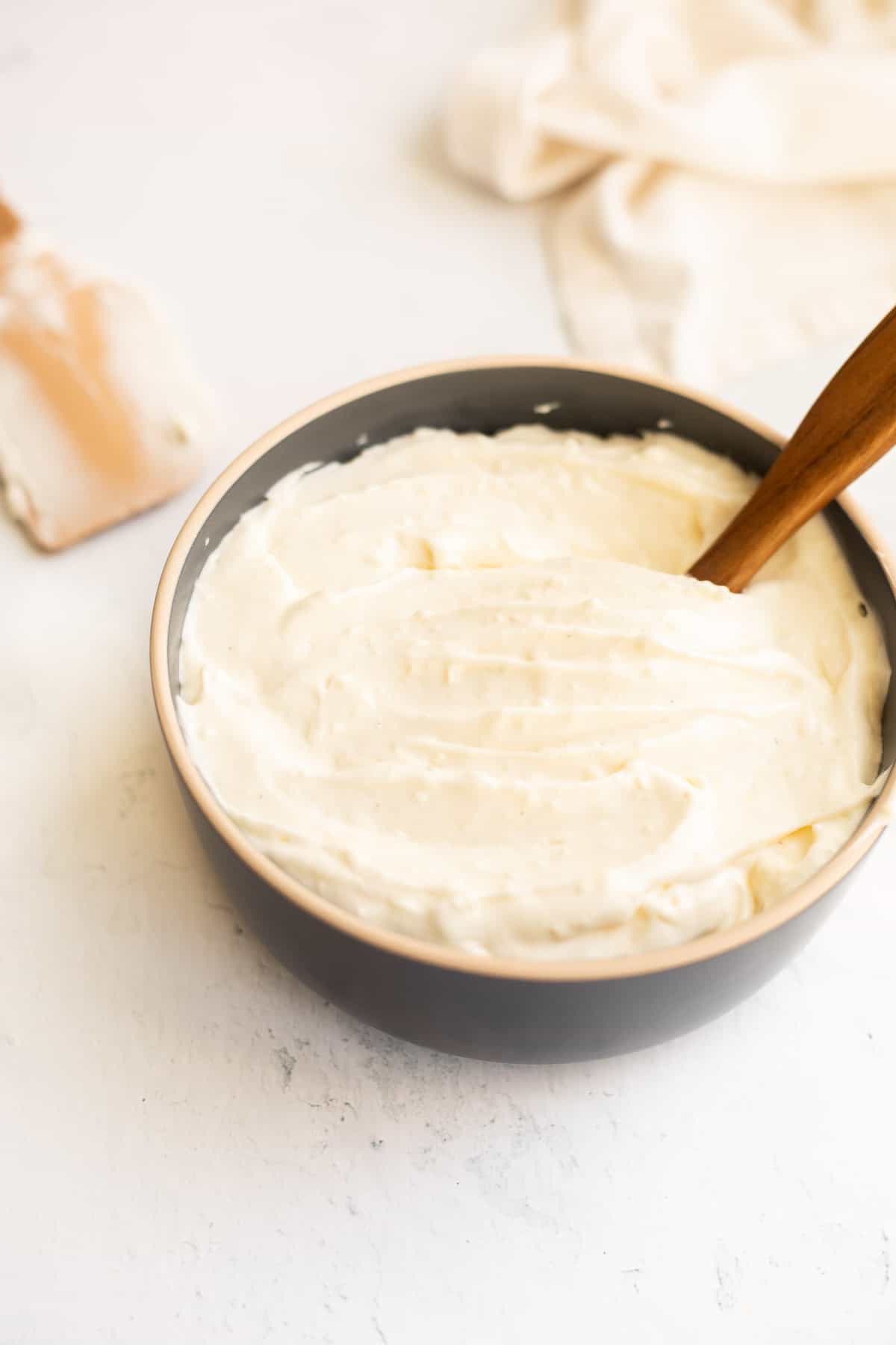 cream cheese frosting without butter in a gray bowl with a wooden spatula.