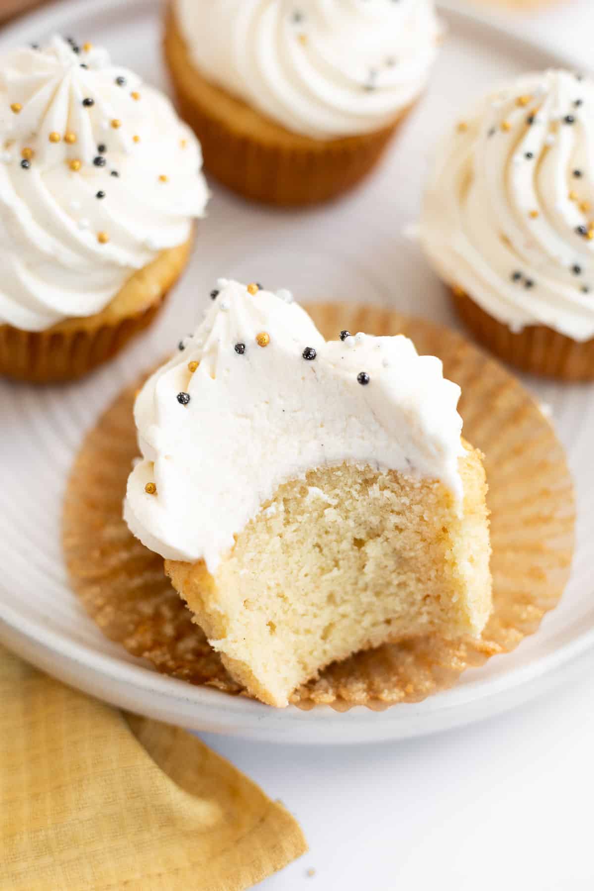 bite in a dairy free vanilla cupcake on a white plate.