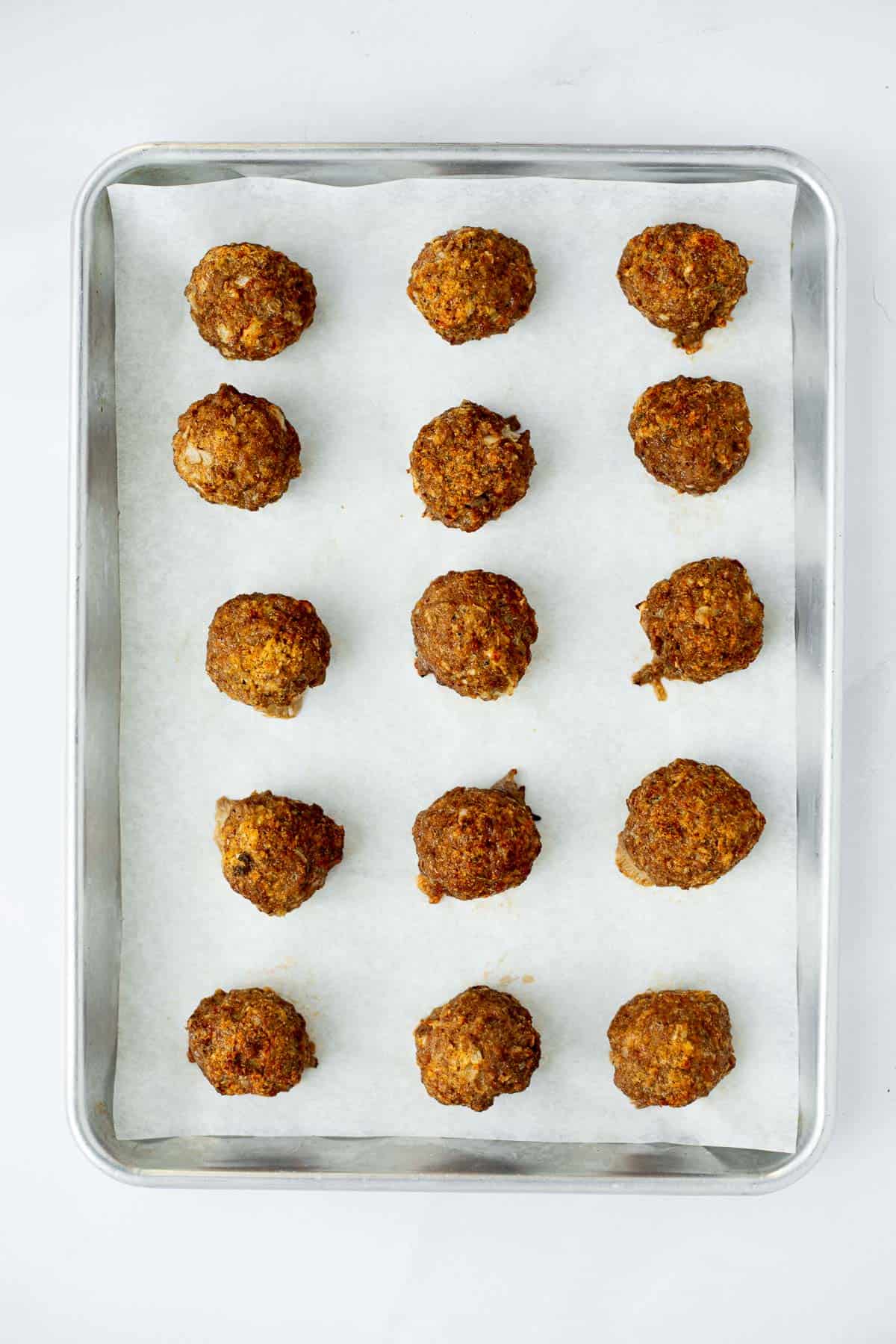 baked gluten free meatballs on a parchment lined baking sheet.