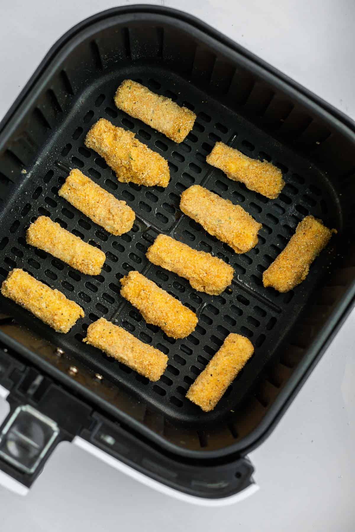 homemade mozzarella sticks in air fryer basket.