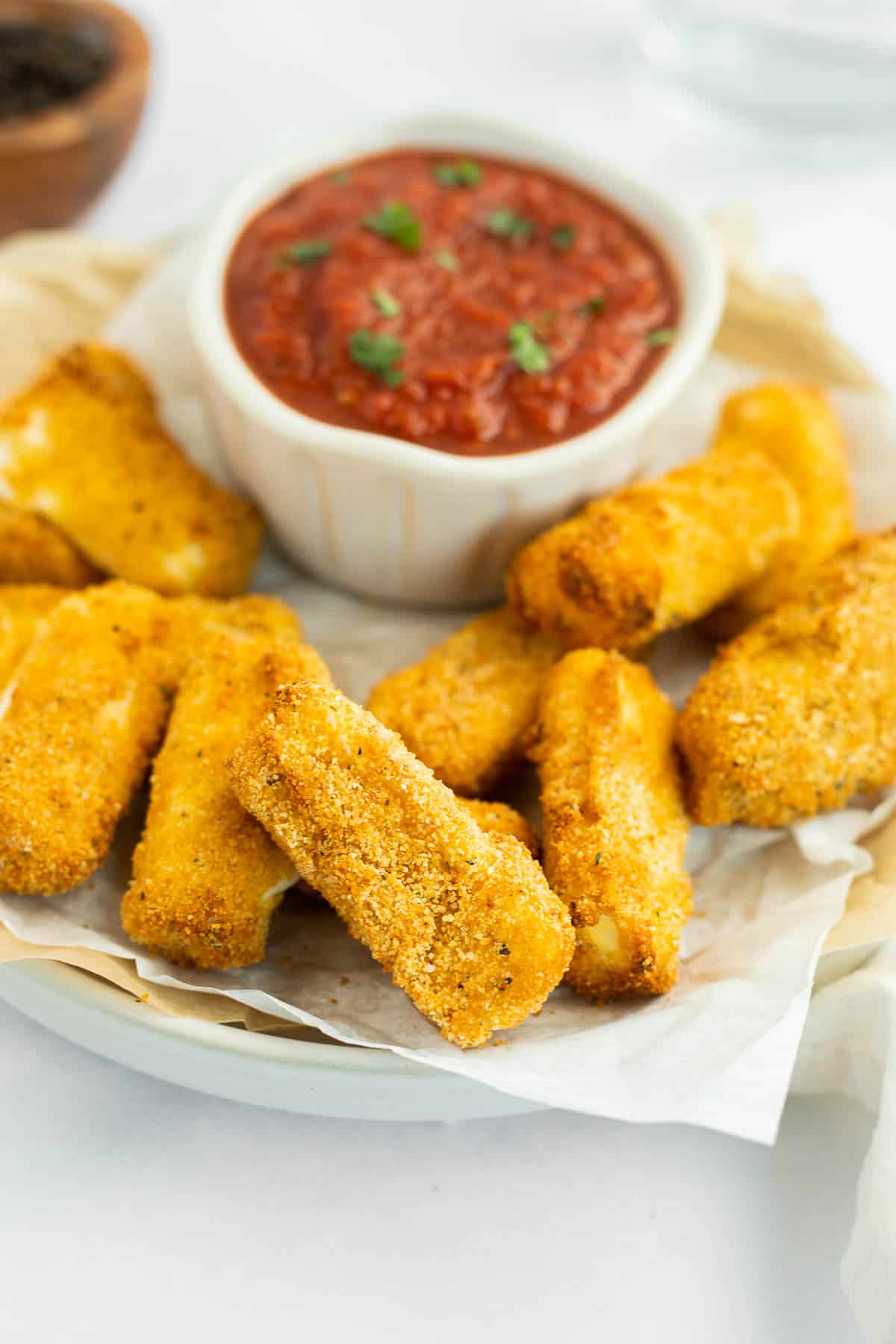 healthy gluten free mozz sticks on parchment lined plate.