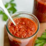 hearty marinara sauce in a glass with a silver spoon.