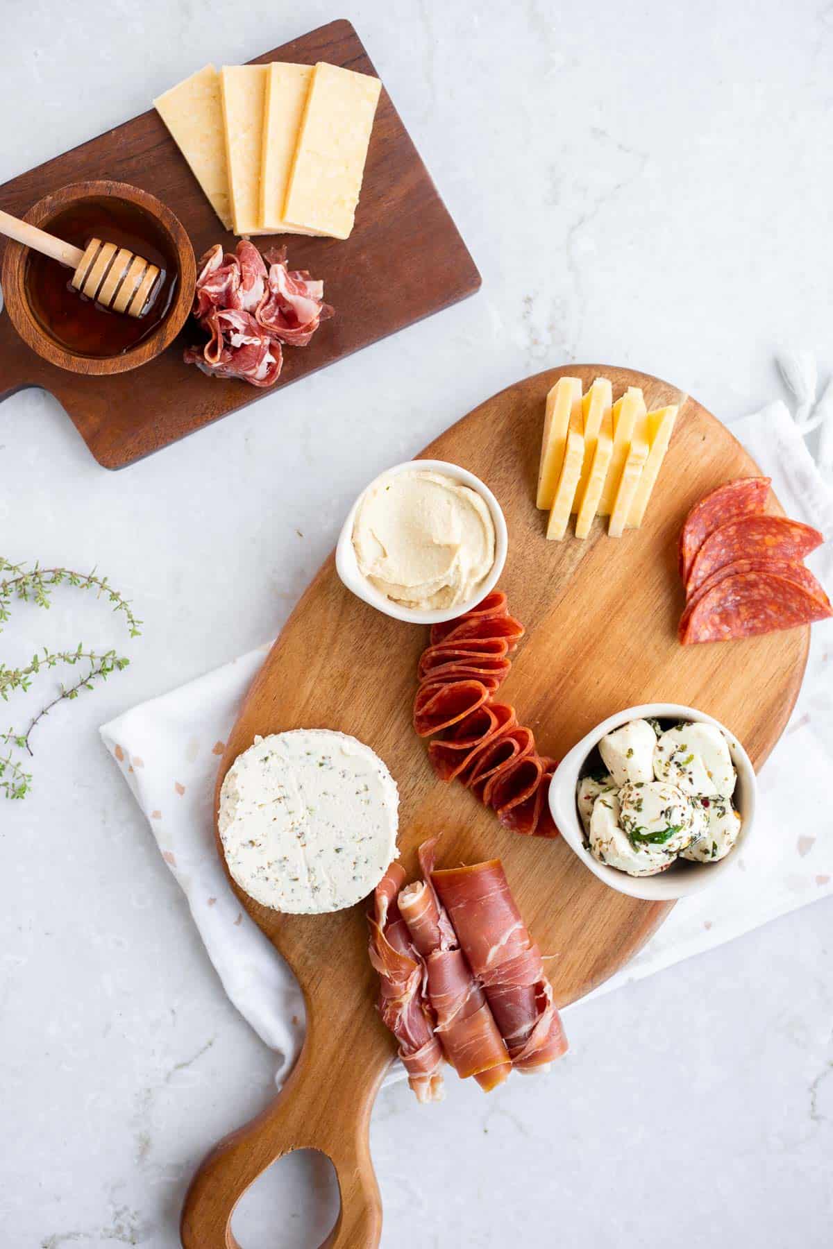 cured meats, cheeses, and hummus on a wooden platter.