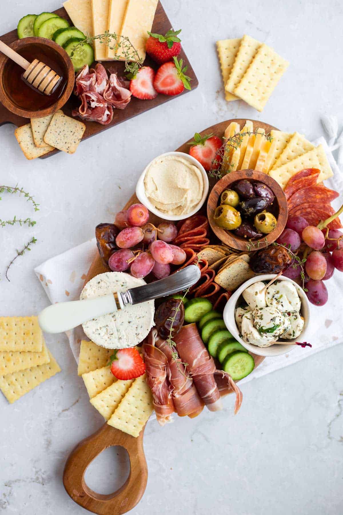 small charcuterie board full of meats, cheese, and vegetables on a white backdrop.