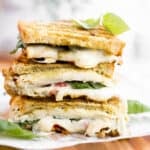 turkey pesto sandwiches stacked on top of each other with meted cheese.
