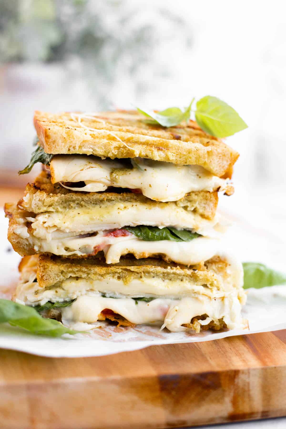 turkey pesto sandwiches stacked on top of each other with meted cheese.