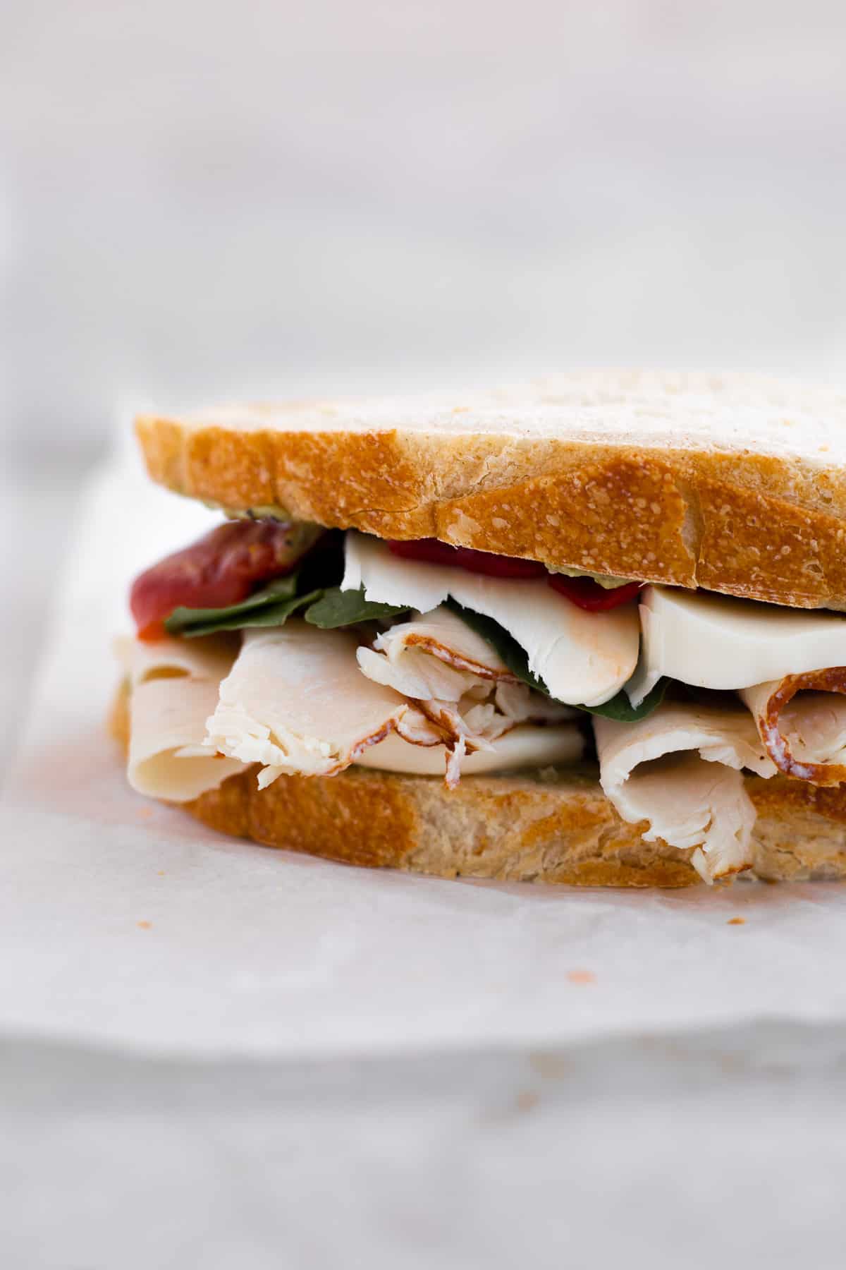 sourdough bread sandwich with turkey, cheese, spinach, and red peppers.