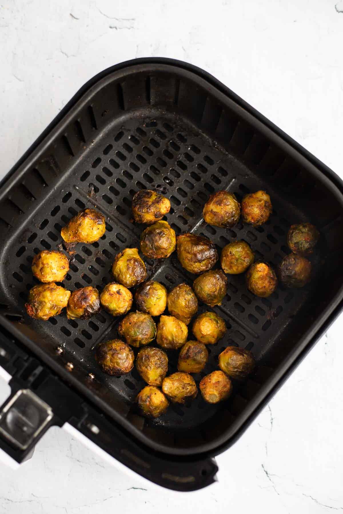 cooked brussels sprouts in air fryer basket.