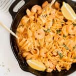 cajun chicken and shrimp pasta in a cast iron skillet with two gold forks.