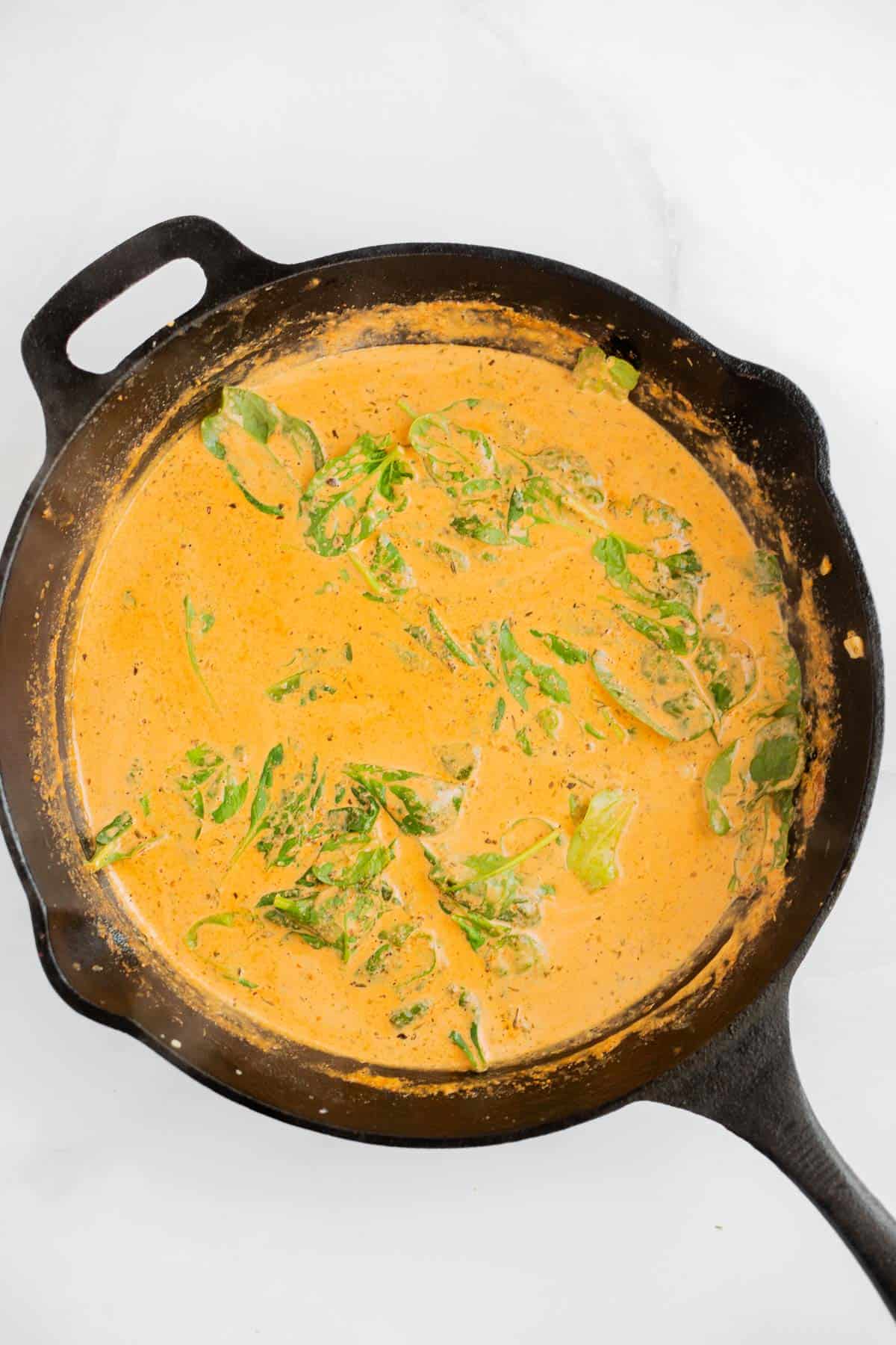 creamy cajun sauce with spinach in a cast iron skillet.