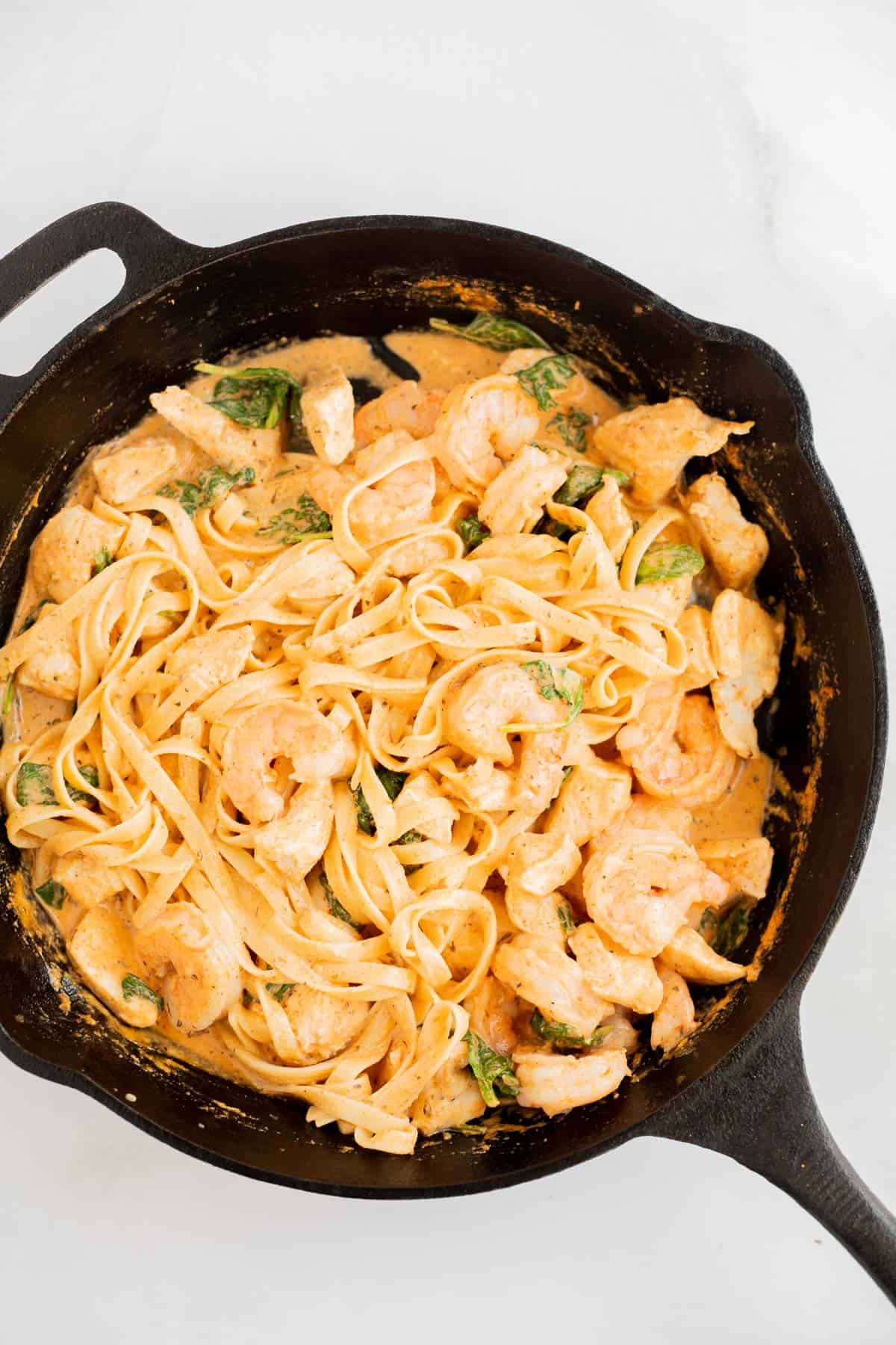Cajun shrimp and chicken pasta in a cast iron skillet.