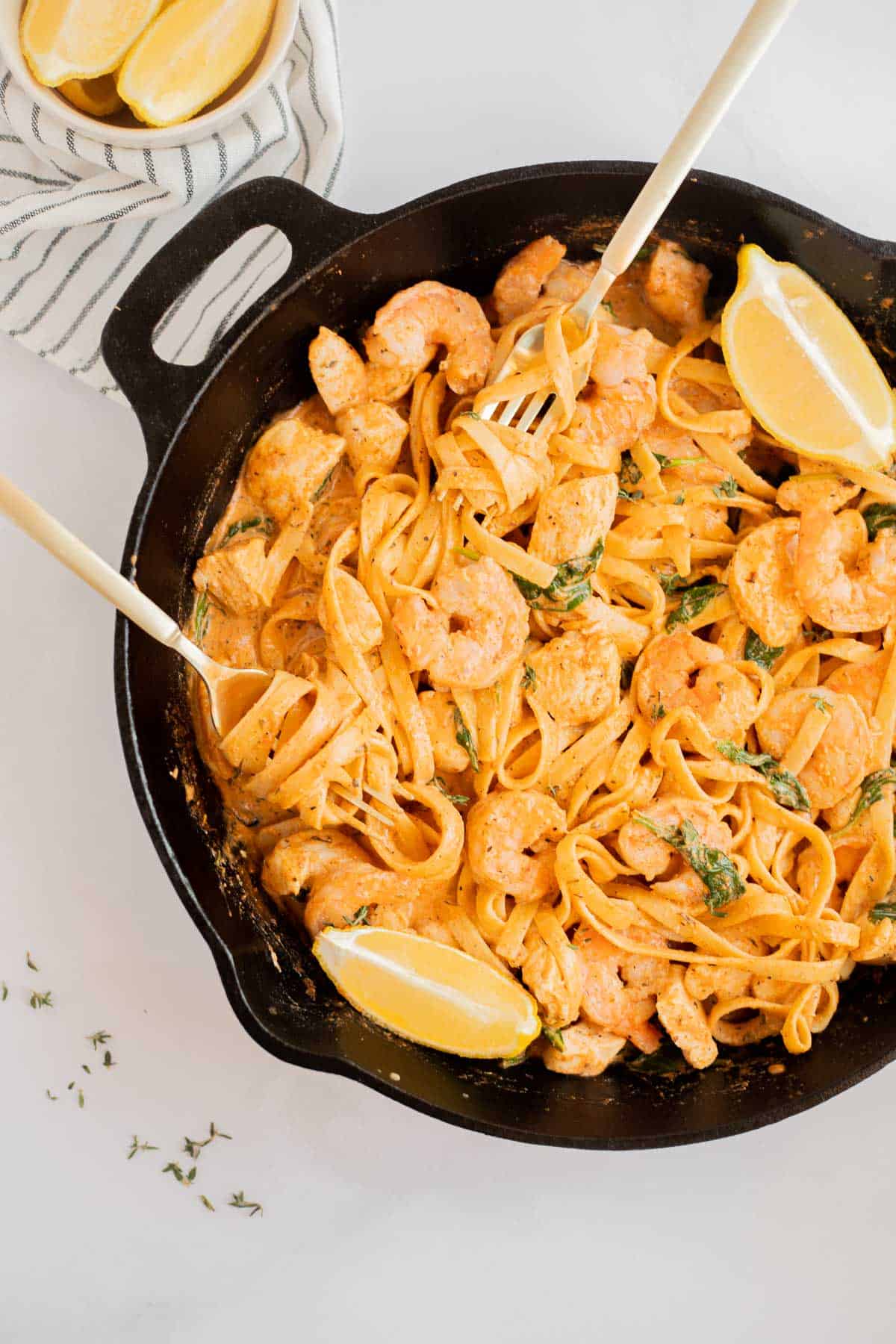 cajun chicken and shrimp pasta in a cast iron skillet with two forks.