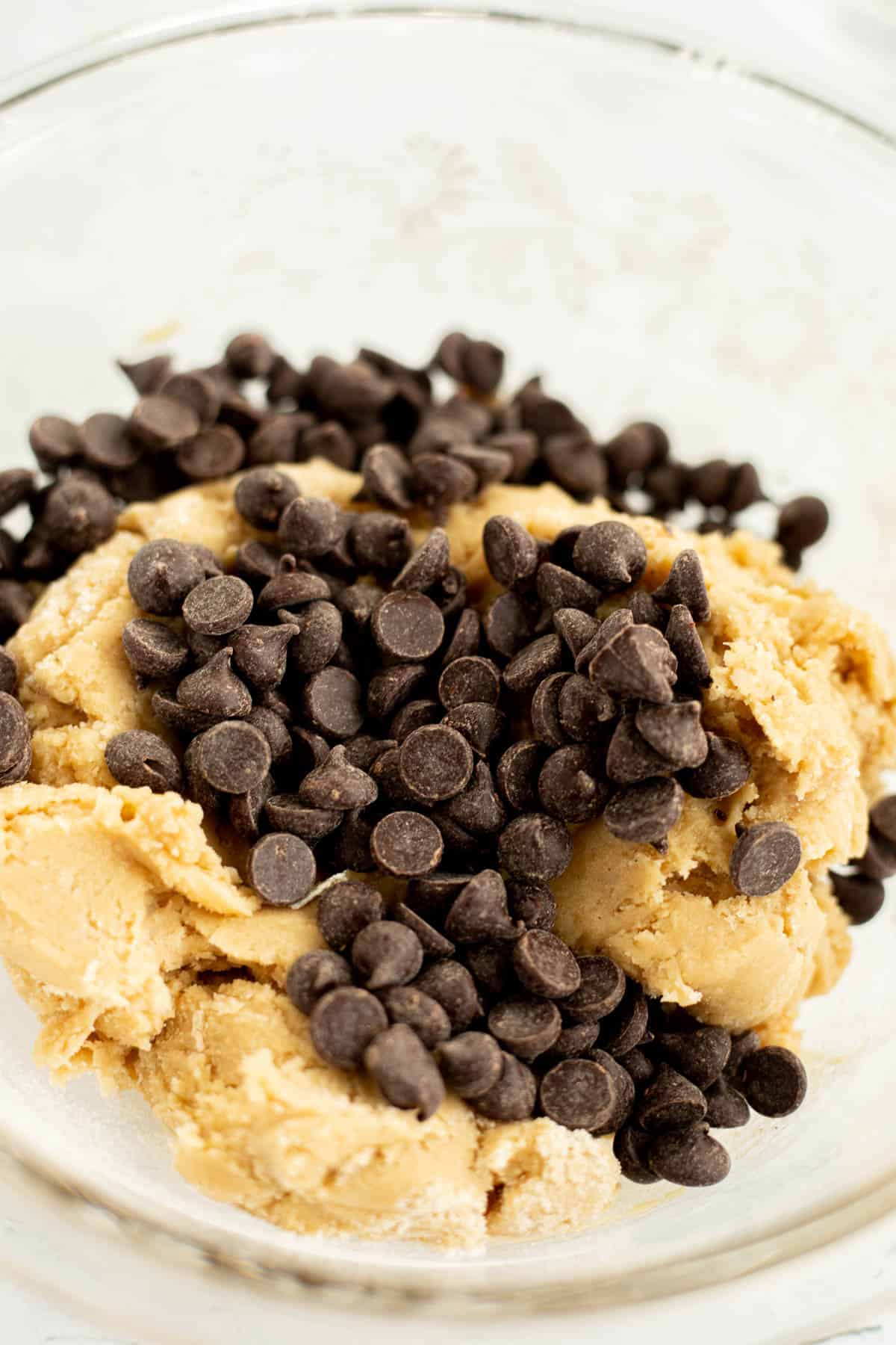 chocolate chips on cookie dough in a glass bowl.