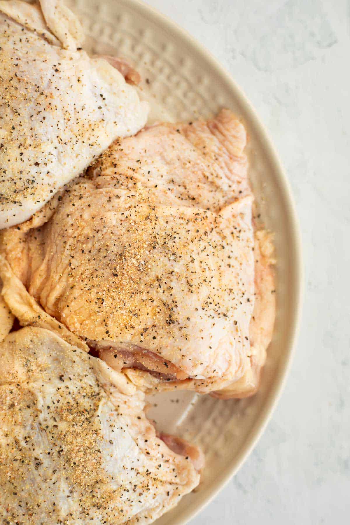 seasoned chicken thighs on a white plate.