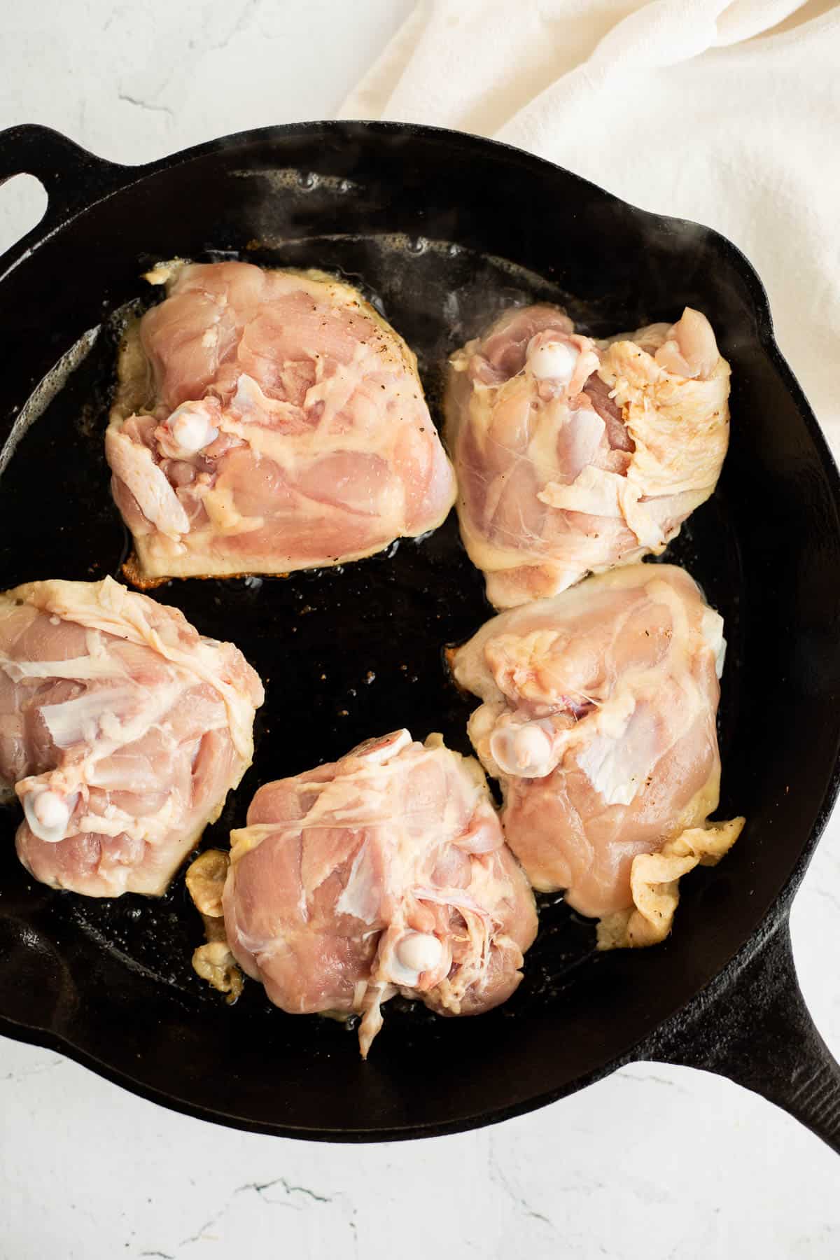 chicken cooking in a cast iron skillet.