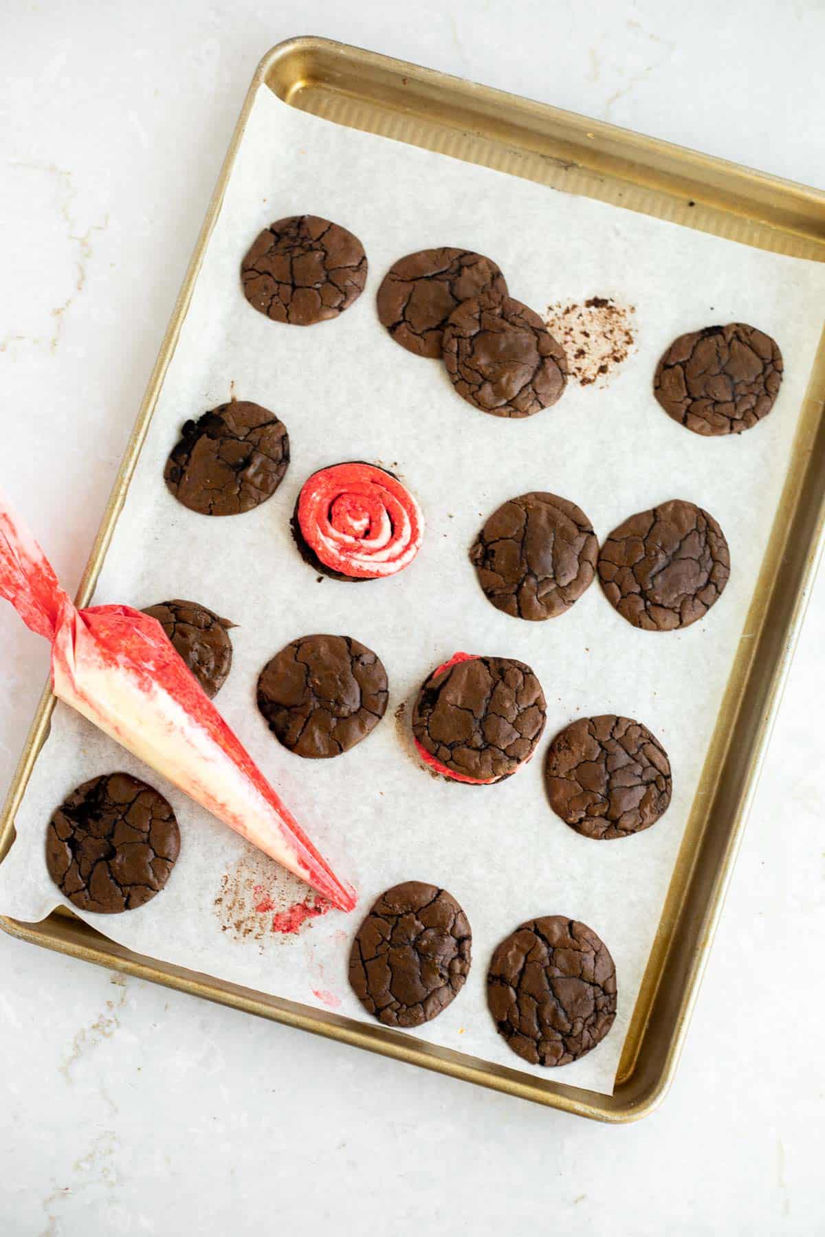 peppermint brownie cookies being assembled on parchment paper.