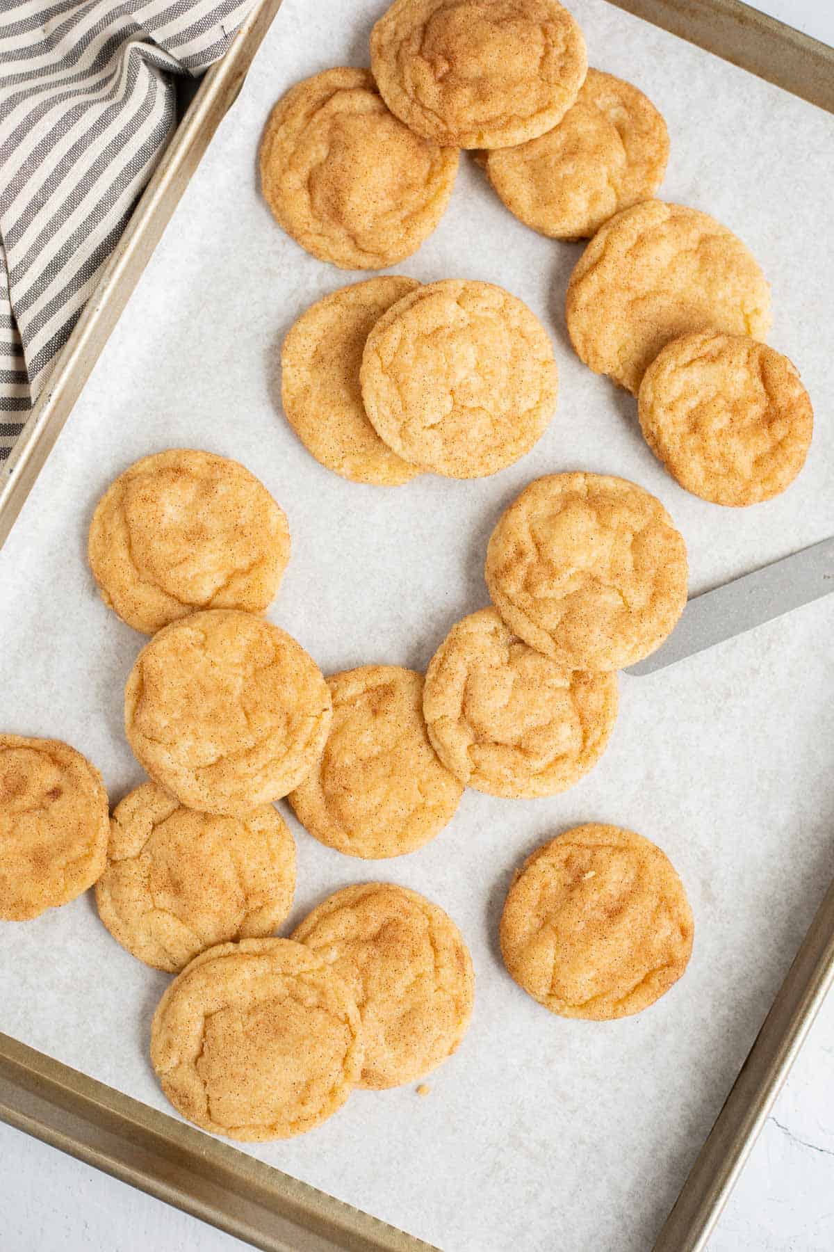 no cream of tartar snickerdoodles spread out on a parchment lined baking sheet.