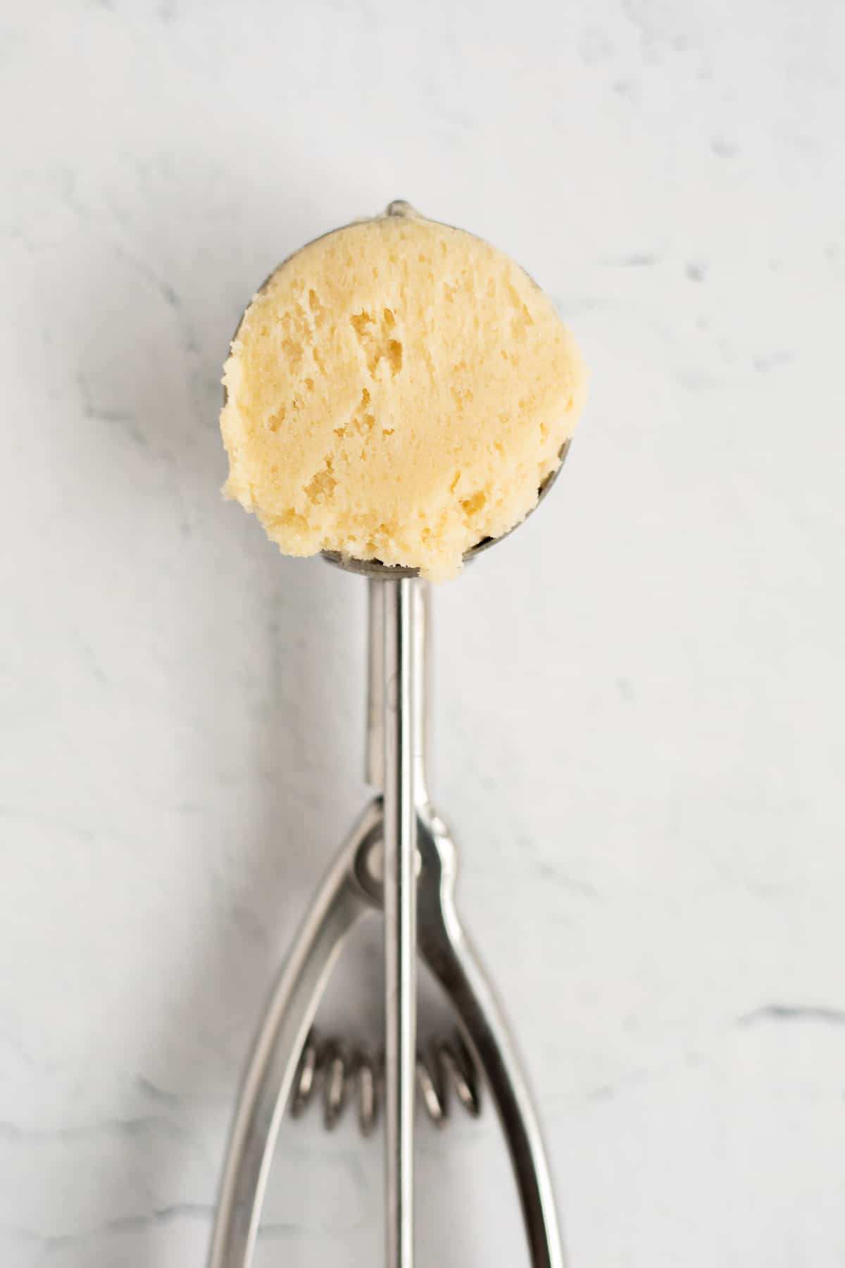 snickerdoodle cookie dough in a silver cookie scoop.