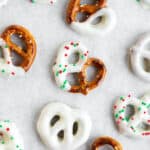 white chocolate pretzel with red and green sprinkles cooling on parchment paper.