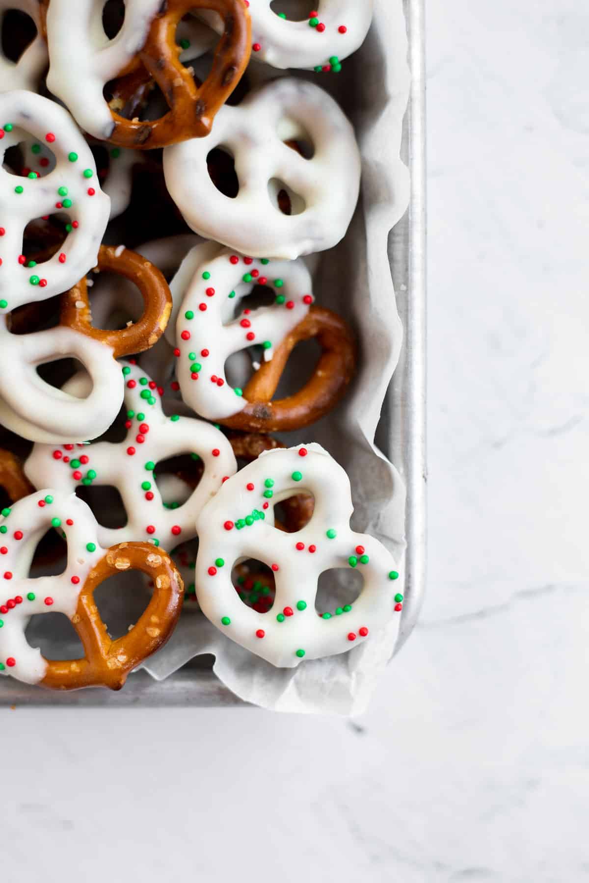 white chocolate covered pretzels piled up on a parchment lined baking sheet.