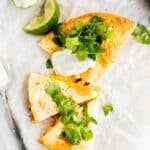 overhead photo of an air fryer quesadilla topped with cilantro and sour cream.