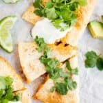 air fryer quesadilla cut into triangles and topped with cilantro and sour cream.