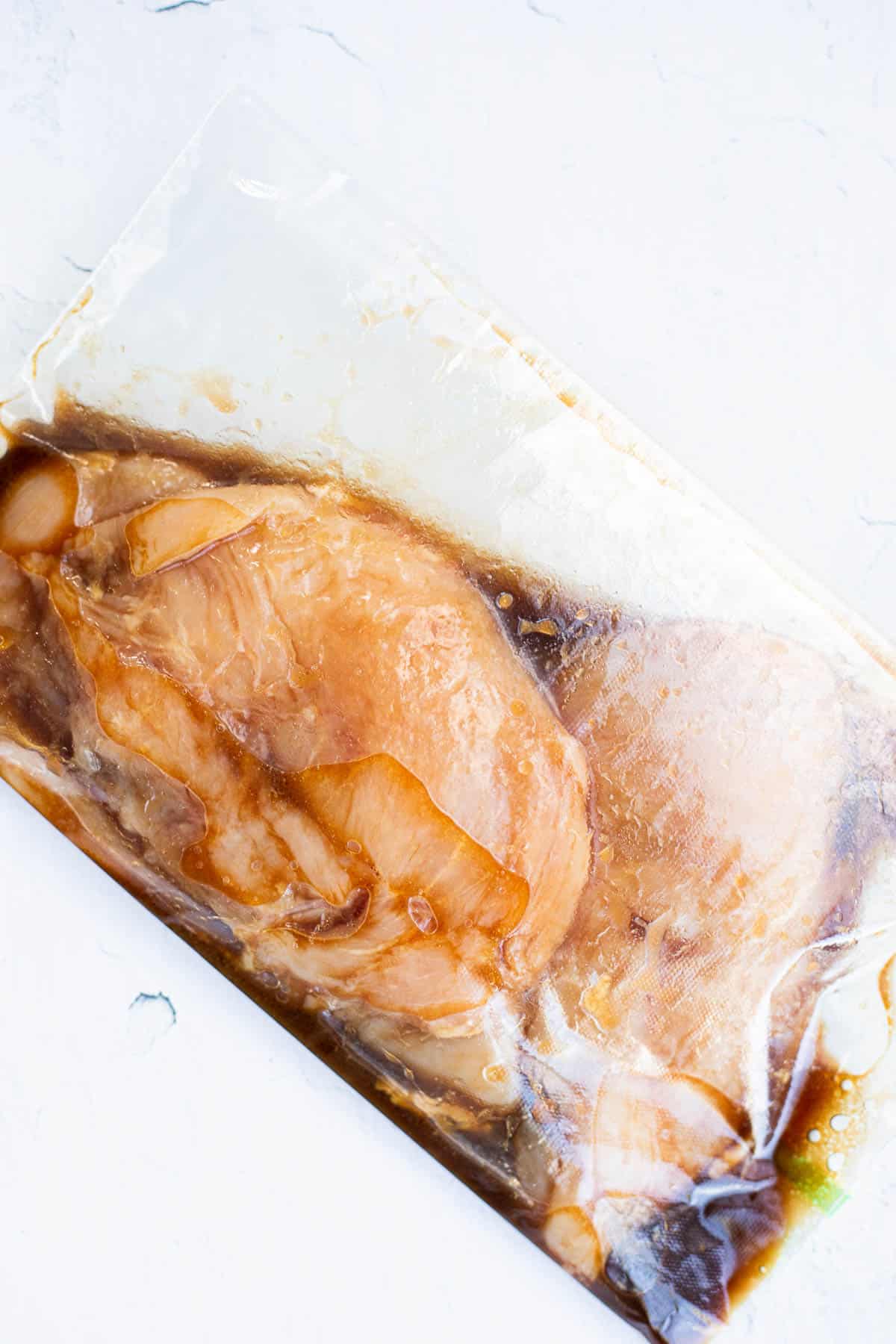 chicken breasts marinating in a plastic bag.