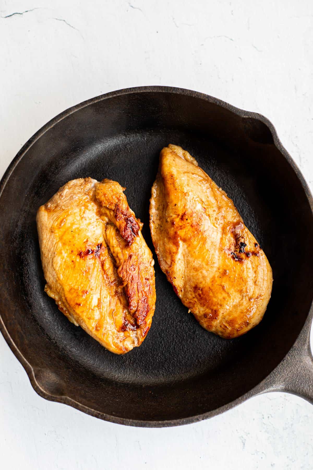 marinated chicken breasts cooked in a cast iron pan.