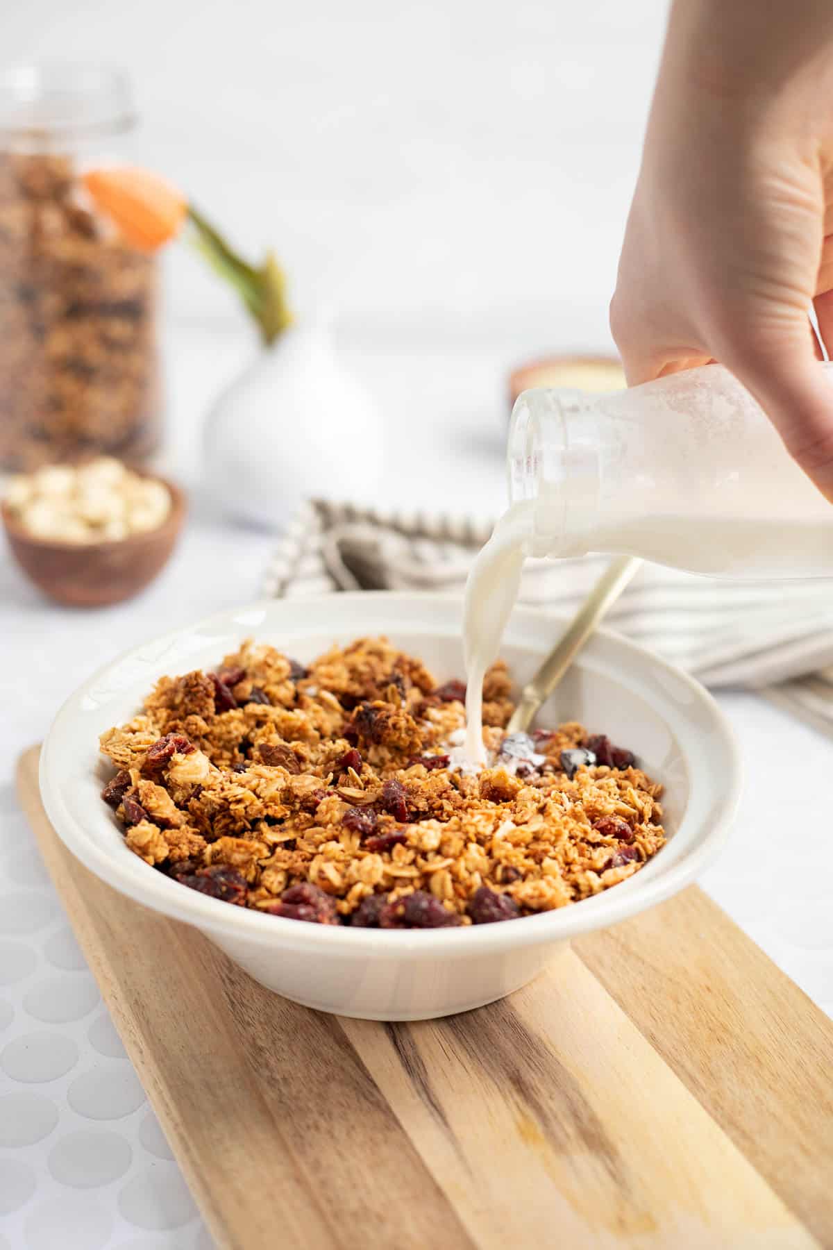 a white bowl of gluten free granola with milk pouring in.