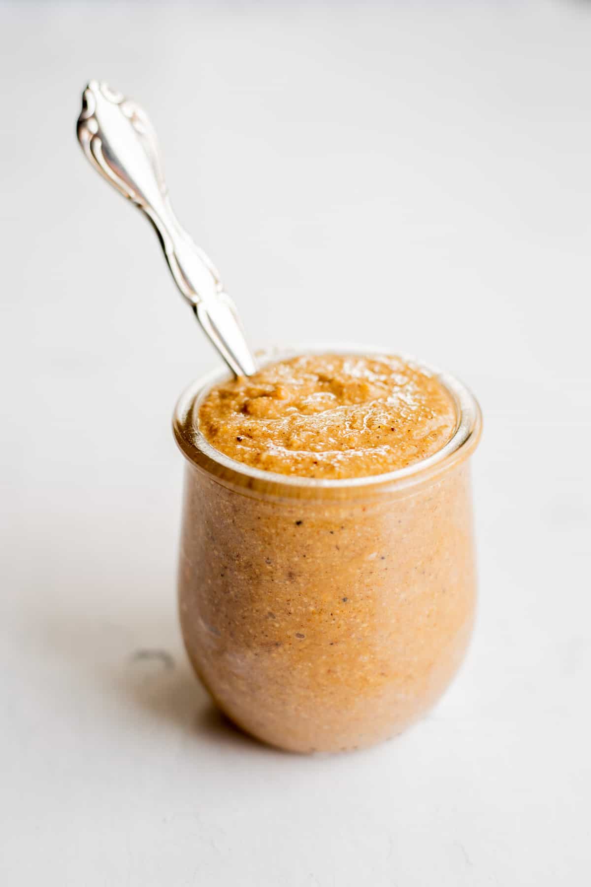 glass jar of oat spread with a silver spoon.