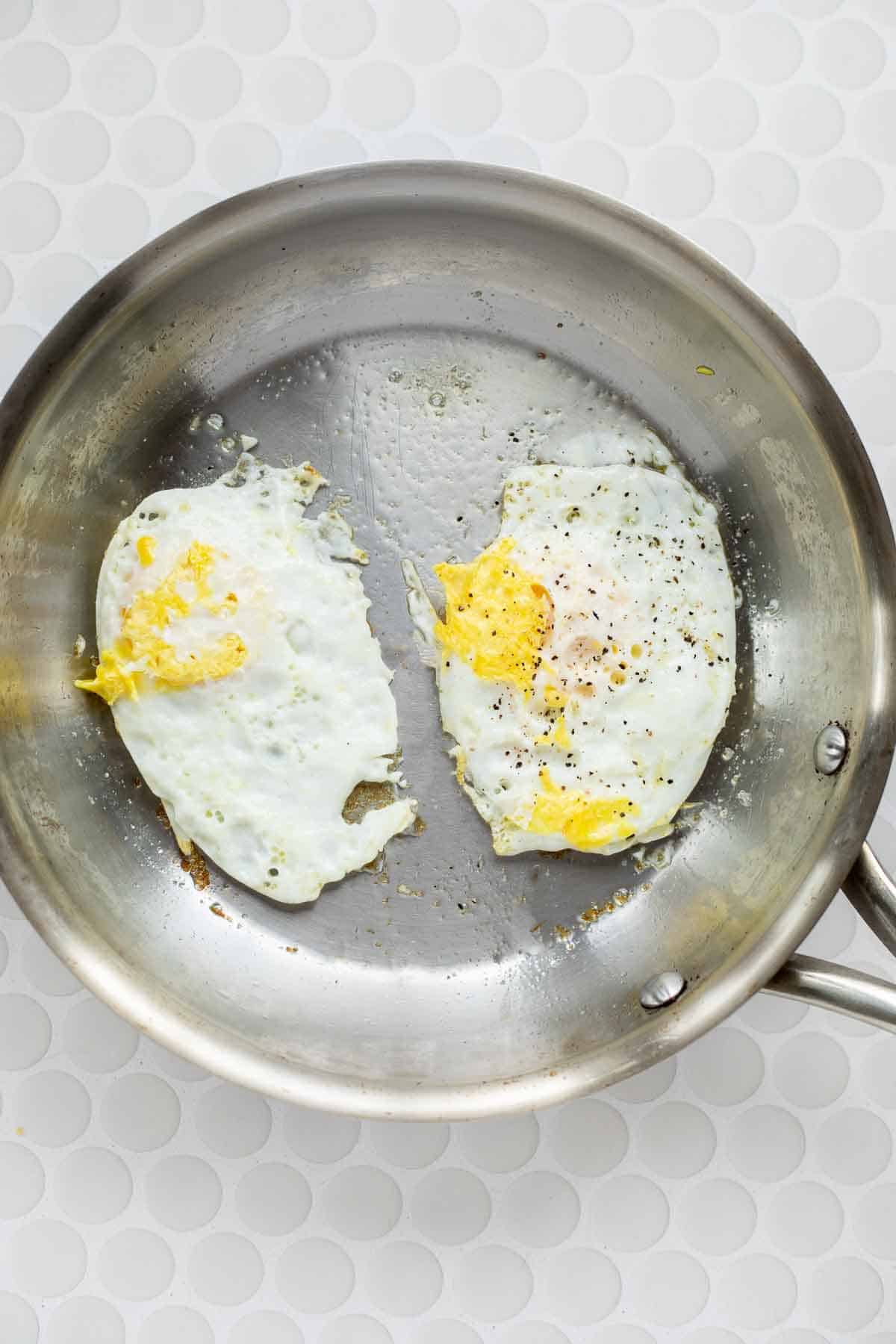 2 eggs cooked over hard in a stainless steel pan.