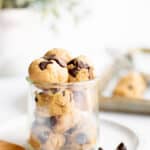 balls of protein cookie dough in a glass jar on a white plate.
