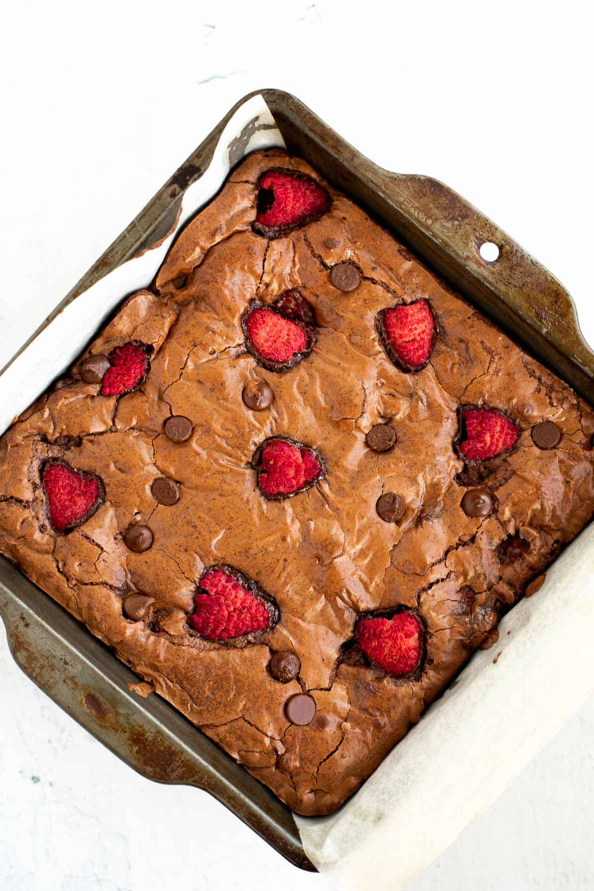 raspberry brownies baked in parchment lined metal baking pan.