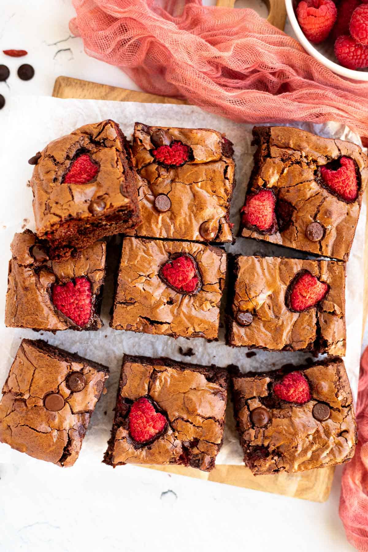 1 batch of raspberry brownies cut into 9 squares on parchment paper.