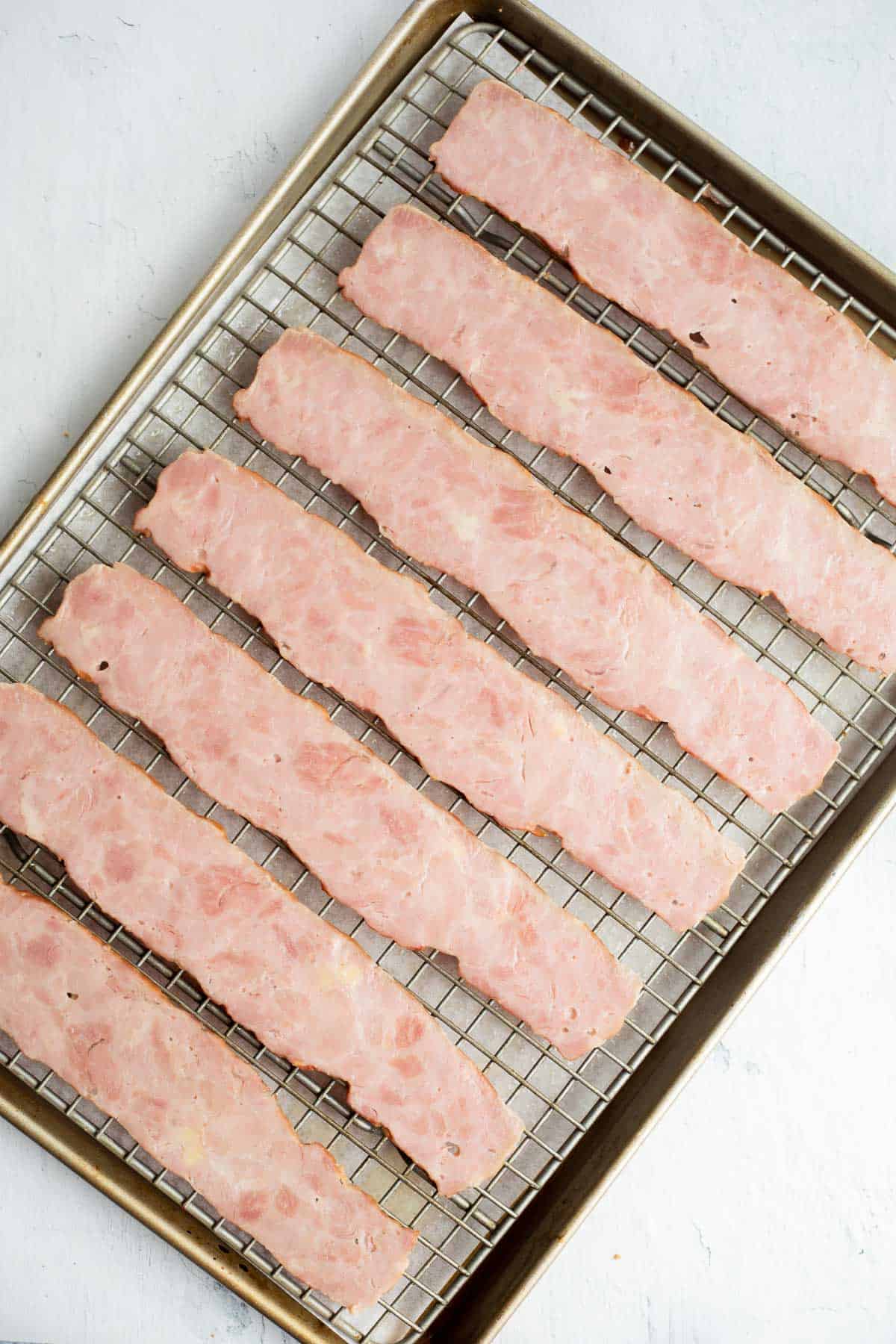 raw rashers of turkey bacon on wire rack in baking sheet.