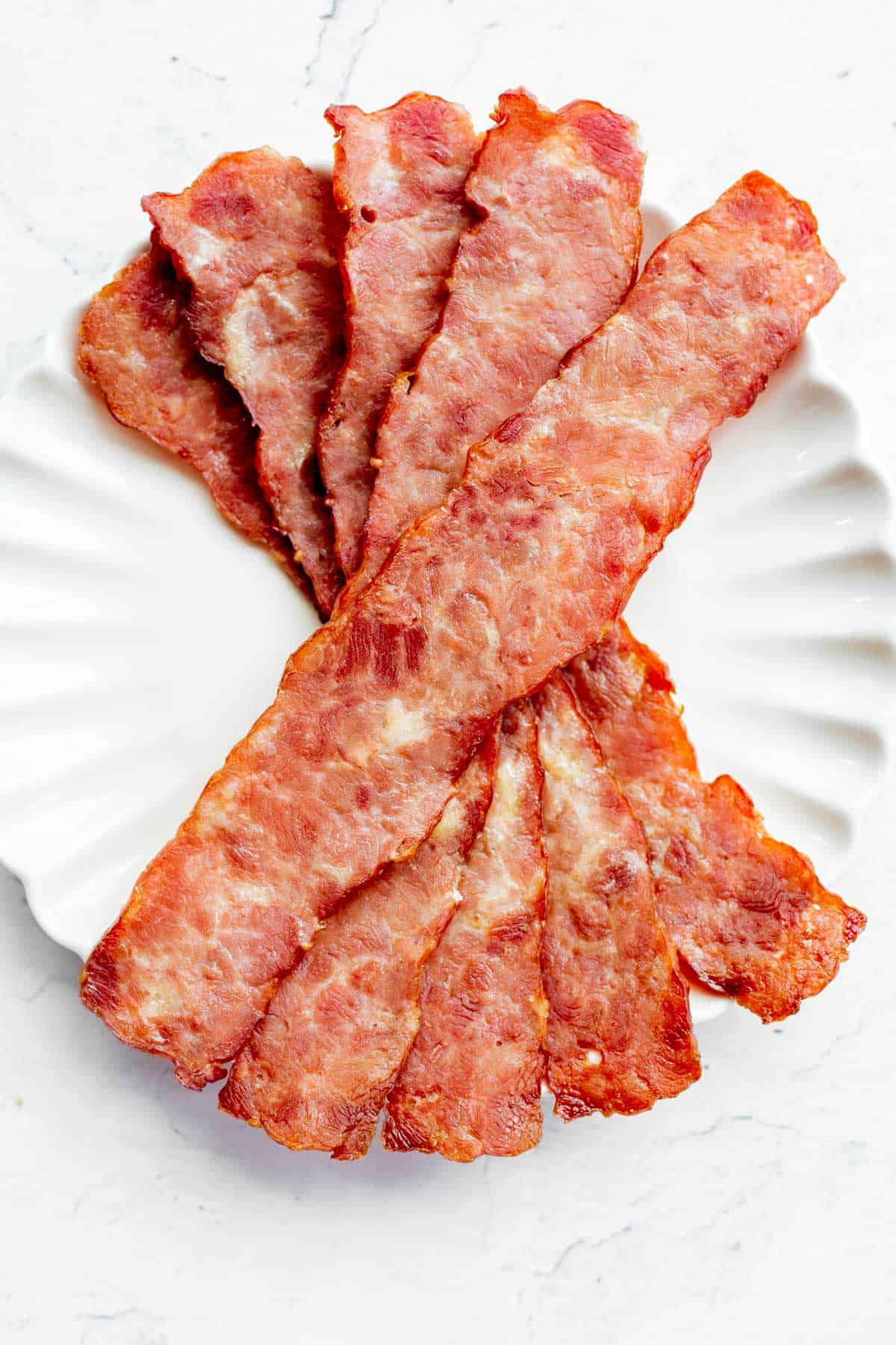 turkey bacon in the oven laid out on a white plate.