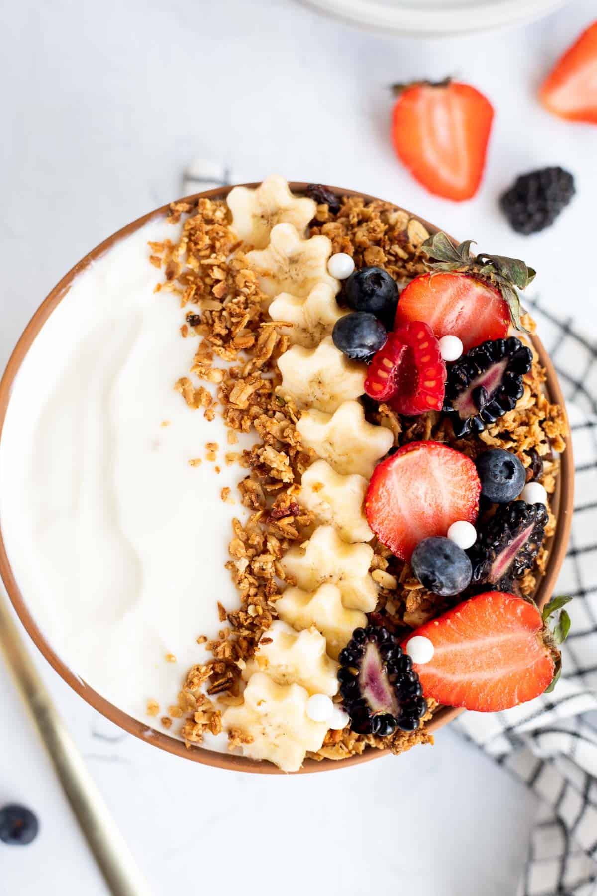 yogurt and granola bowl topped with assorted berries and banana slices.