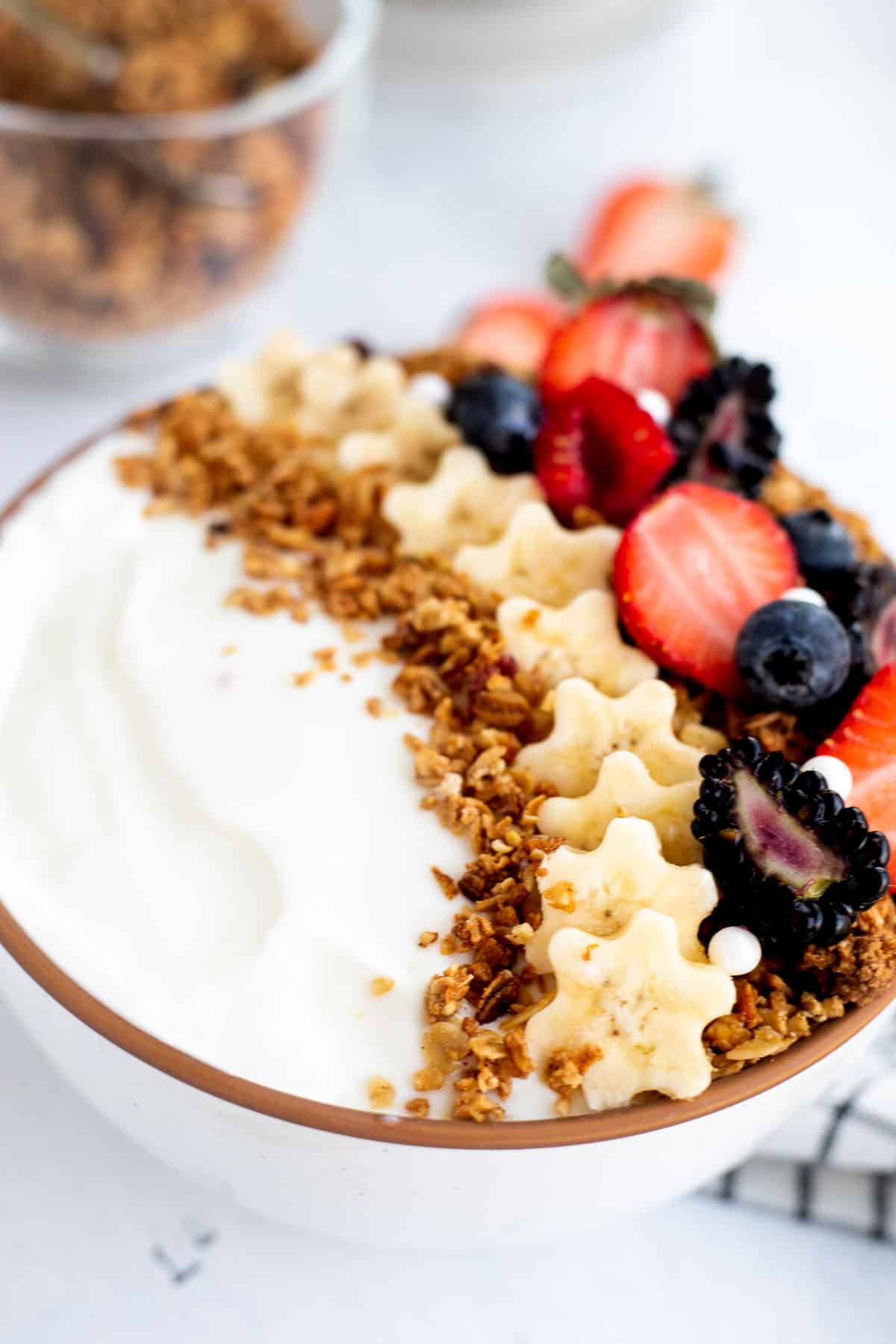 yogurt with granola, sliced bananas, and berries cut in half.