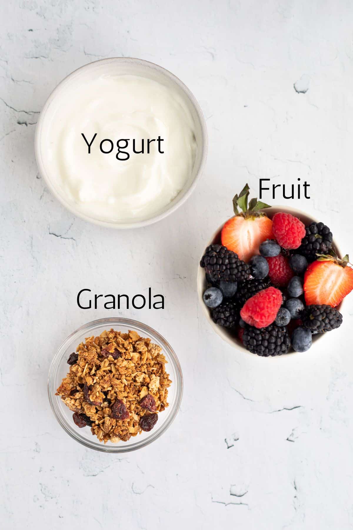 ingredients for a yogurt and granola bowl labeled with black text.