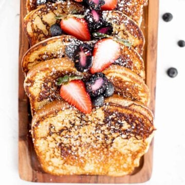 protein french toast slices topped with fresh fruit and powdered sugar.