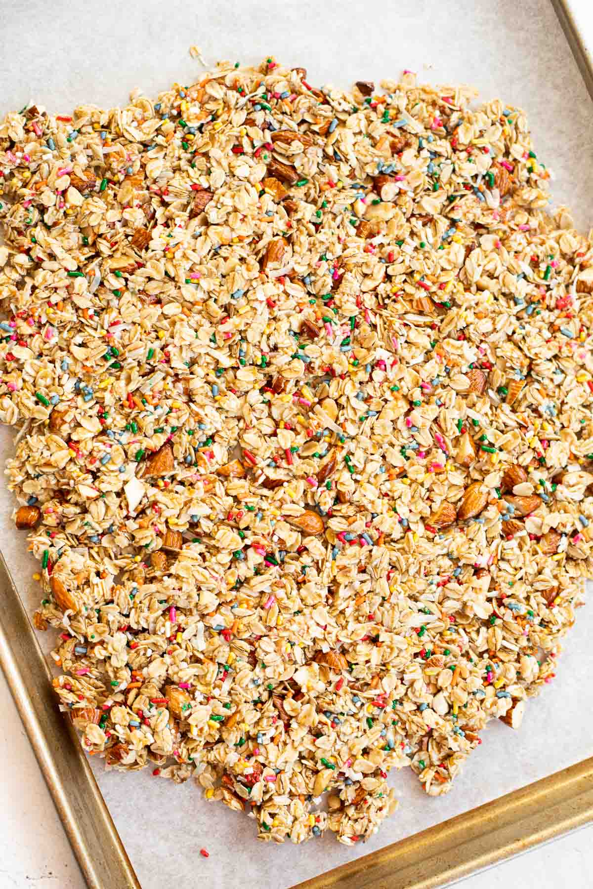 cake batter granola pressed into an even layer on parchment paper.