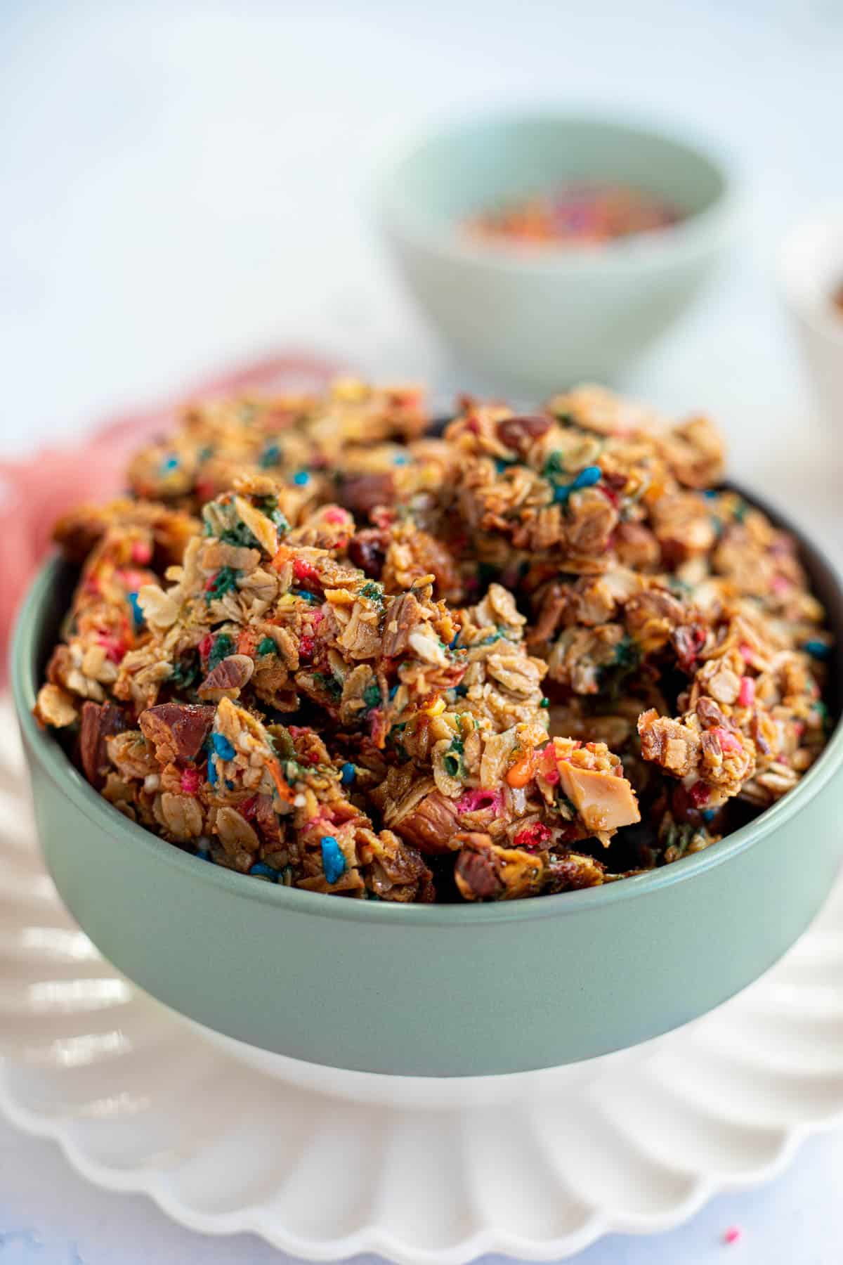 a green bowl of birthday cake granola broken into clusters.