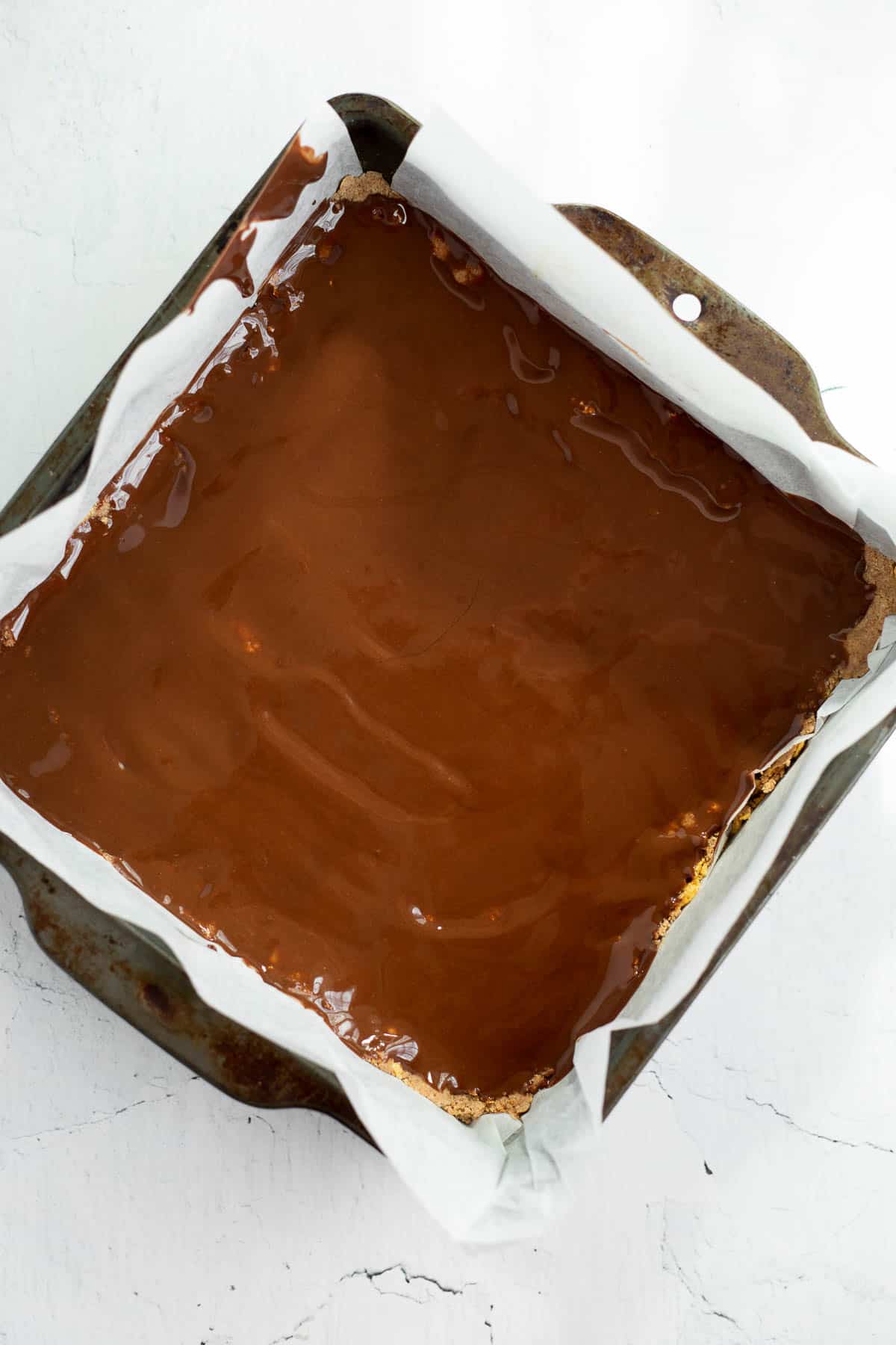 melted chocolate spread on energy bars in baking dish.