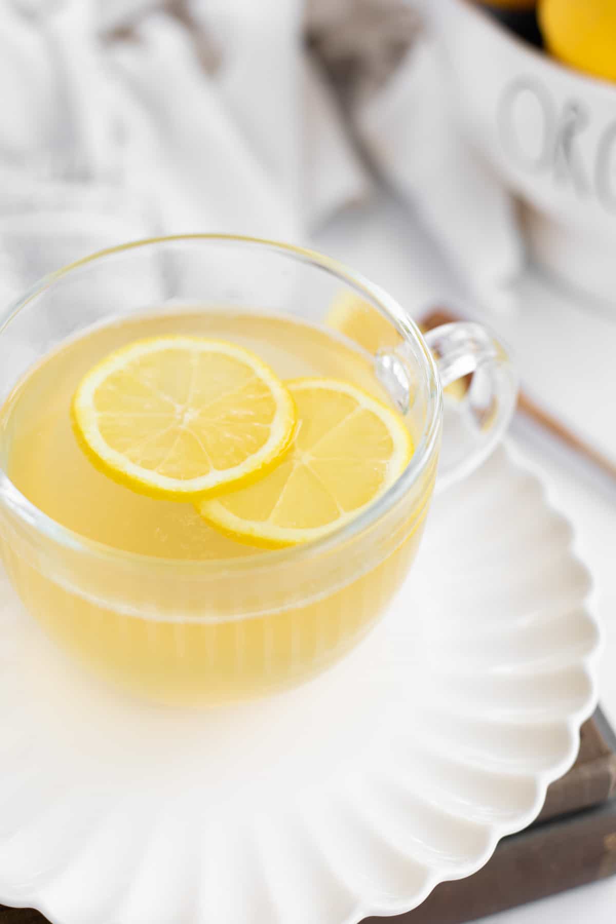 honey lemon tea in a clear cup on a white plate.